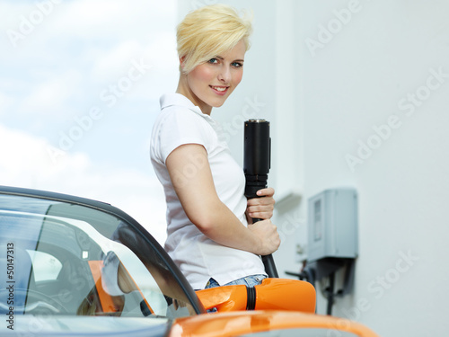 Photo: Pretty woman is loading electrically powered car outdoors Pretty woman is loading electrically powered car outdoors