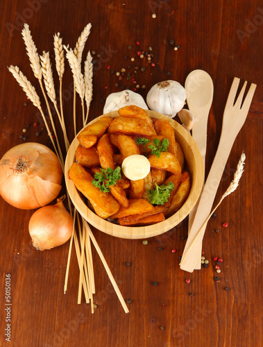 Photo: Appetizing village potatoes in bowl on wooden table close-up Appetizing village potatoes in bowl on wooden table close-up