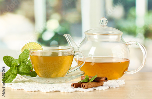 Photo: Cup of tea with mint,lime and cinnamon on table in room Cup of tea with mint,lime and cinnamon on table in room
