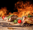 Grilled beef steaks with flames on background