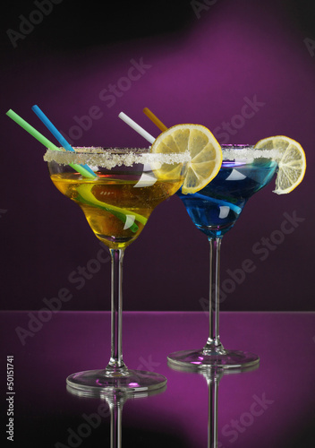Photo: Yellow and blue cocktails in glasses on color background Yellow and blue cocktails in glasses on color background