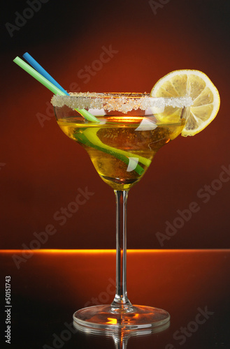 Photo: Yellow cocktail in glass on color background Yellow cocktail in glass on color background