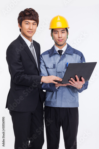 Photo: Business man and engineer looking laptop. Business man and engineer looking laptop.