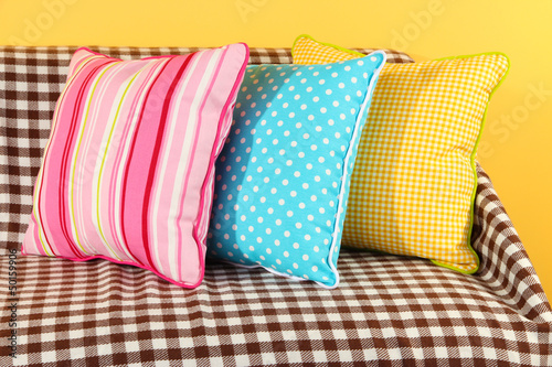 Photo: Colorful pillows on couch on yellow background Colorful pillows on couch on yellow background