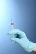 Doctor holding syringe with a vaccine, on blue background