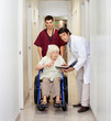 Medical Professionals With Patient In Corridor
