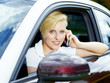 Foto: Blond girl sitting in her car has a call with smartphone Blond girl sitting in her car has a call with smartphone