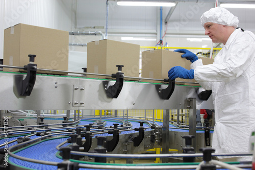 Photo: caucasian man worker in white apron at packing line in factory caucasian man worker in white apron at packing line in factory