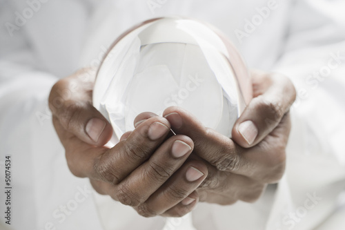 Photo: Close up of mixed race man holding crystal ball Close up of mixed race man holding crystal ball