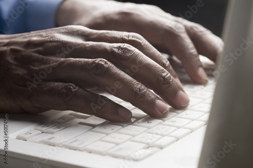 Photo: Mixed race man typing on laptop Mixed race man typing on laptop