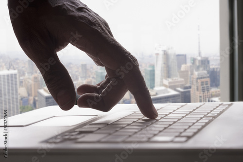 Photo: Mixed race man typing on laptop Mixed race man typing on laptop