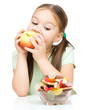 Little girl choosing between apples and sweets