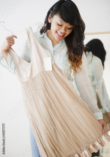 Photo: Pacific Islander woman looking at dress in store Pacific Islander woman looking at dress in store