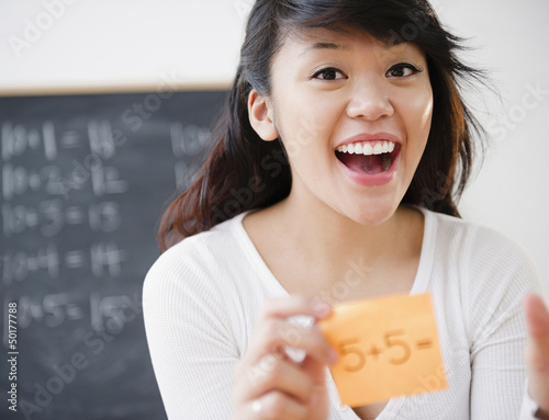 Photo: Pacific Islander teacher holding sticky note with math problem Pacific Islander teacher holding sticky note with math problem