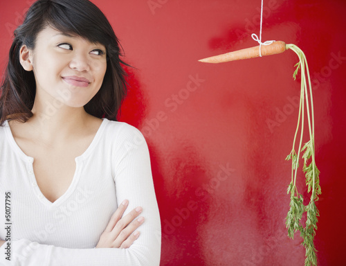 Photo: Pacific Islander woman looking at a carrot on a string Pacific Islander woman looking at a carrot on a string