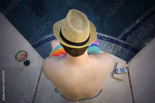 Photo: Man sitting at poolside Man sitting at poolside
