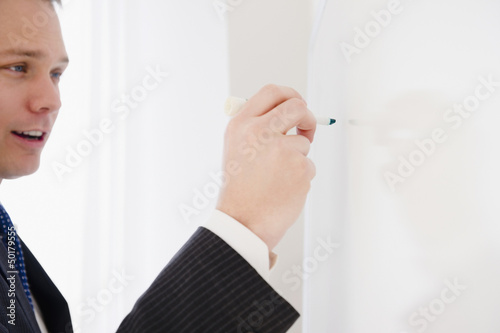 Photo: Caucasian businessman writing on whiteboard Caucasian businessman writing on whiteboard