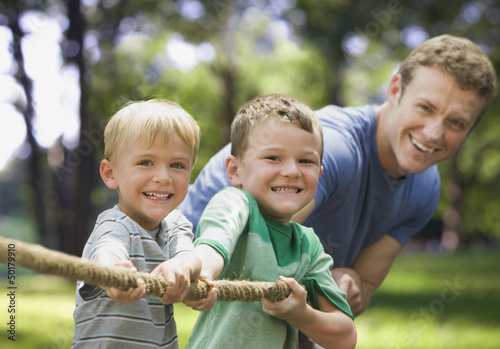 Photo: Caucasian father and sons playing tug-of-war Caucasian father and sons playing tug-of-war