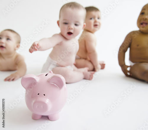 Photo: Babies sitting on floor with piggy bank Babies sitting on floor with piggy bank