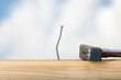 Crooked nail in the wooden board with a hammer