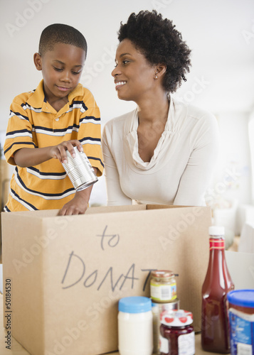 Photo: Black mother and son boxing food for donation Black mother and son boxing food for donation