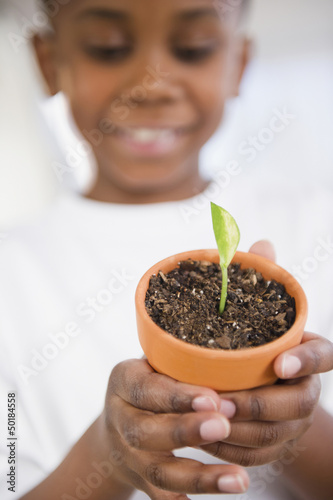 Photo: Black boy holding seedling in pot Black boy holding seedling in pot