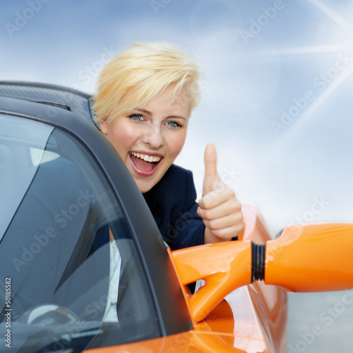 Photo: Pretty girl driving a roadster in summer and shows thumb up Pretty girl driving a roadster in summer and shows thumb up