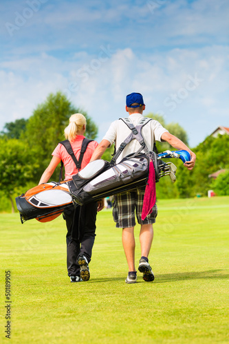 Photo: Young sportive couple playing golf on a course Young sportive couple playing golf on a course