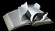 Bible pages turning in the wind on black background