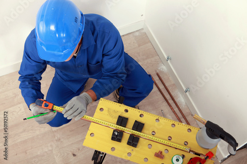 Photo: Top-view of plumber measuring copper pipe Top-view of plumber measuring copper pipe