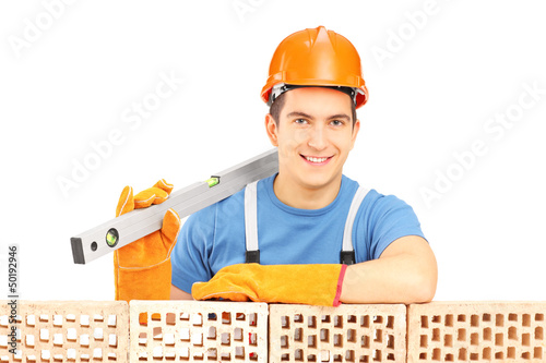 Photo: Male construction worker holding a bubble level and resting on a Male construction worker holding a bubble level and resting on a