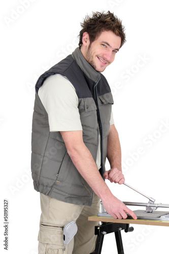 Photo: Man with a tile cutter Man with a tile cutter