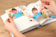 Photos in hands and photo album on wooden table