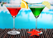 Glasses of cocktails on table near pool
