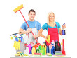 Male and female cleaners posing with cleaning supplies on a tabl