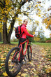 Woman cyclist with bike and backpack bicycle walk in park