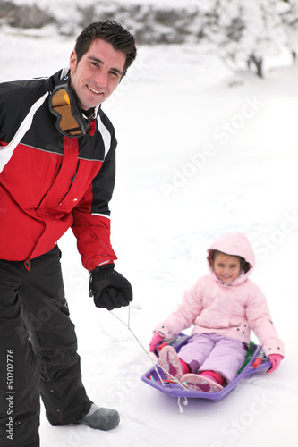 Photo: Father pulling daughter on sledge Father pulling daughter on sledge