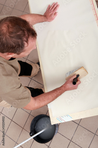 Photo: Handyman applying glue on wallpaper Handyman applying glue on wallpaper