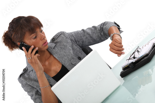 Photo: businesswoman talking on her cell and looking at her watch businesswoman talking on her cell and looking at her watch