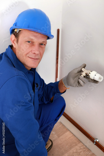 Photo: Workman holding a radiator temperature dial Workman holding a radiator temperature dial