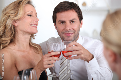 Photo: Couple sitting holding wine glasses together Couple sitting holding wine glasses together