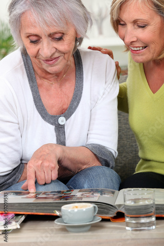 Photo: Two women looking through family photo album Two women looking through family photo album