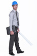 tired businessman wearing helmet and holding a blueprint