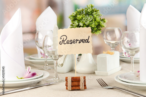 Photo: Reserved sign on restaurant table with empty dishes and glasses Reserved sign on restaurant table with empty dishes and glasses