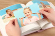 Photos in hands and photo album on wooden table