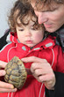 Father and son holding turtle