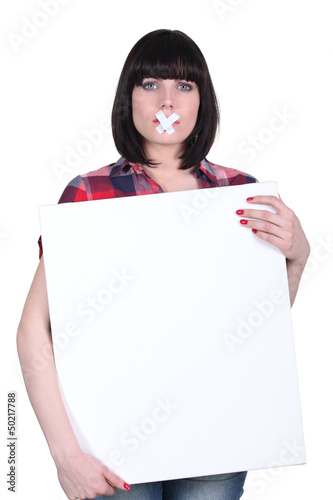 Photo: Woman with bandage on mouth holding panel Woman with bandage on mouth holding panel