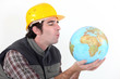 Construction worker blowing on globe