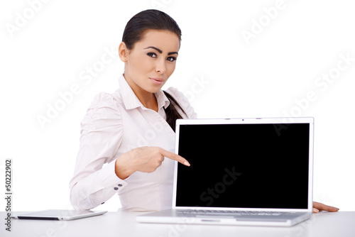 Photo: Business woman sitting at her desk with laptop Business woman sitting at her desk with laptop