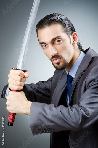 Photo: Angry businessman with sword in dark room Angry businessman with sword in dark room
